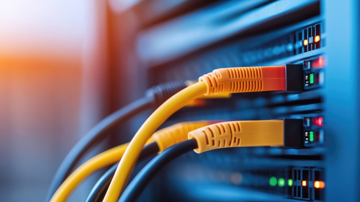 Yellow network cables plugged into a lit server rack