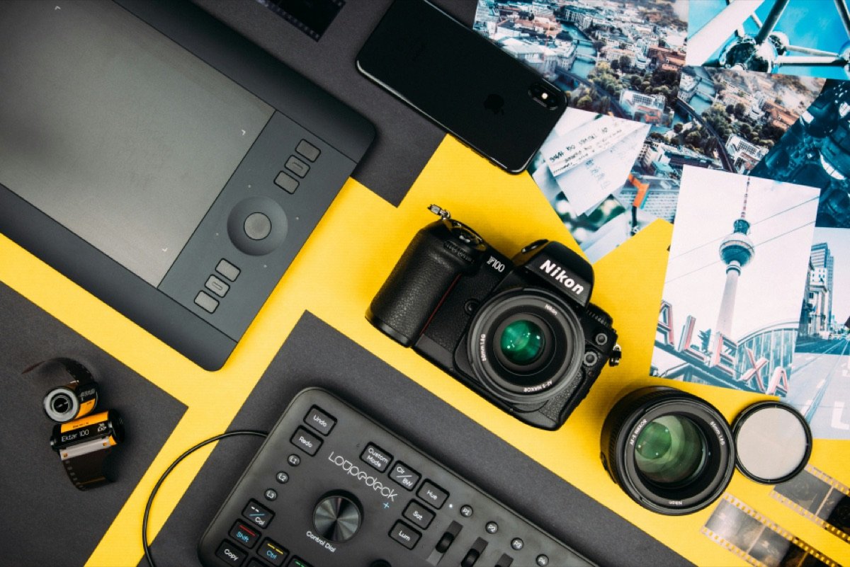 A camera, lens, drawing tablet and editing console on a desk, from above