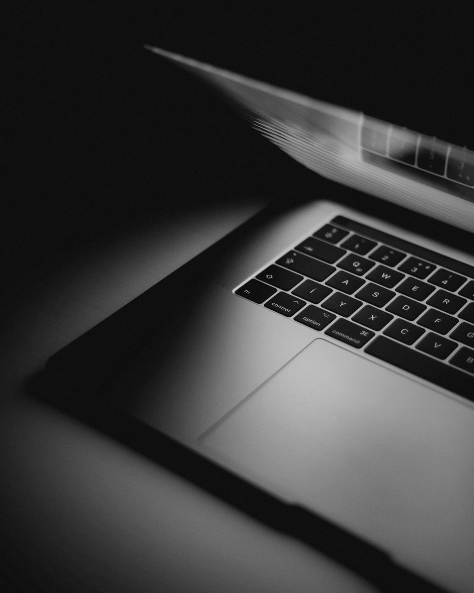 A laptop half open in the dark, its keyboard lit