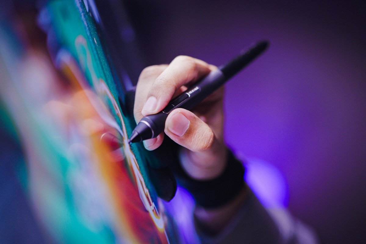 A hand drawing with a stylus on a colourful screen