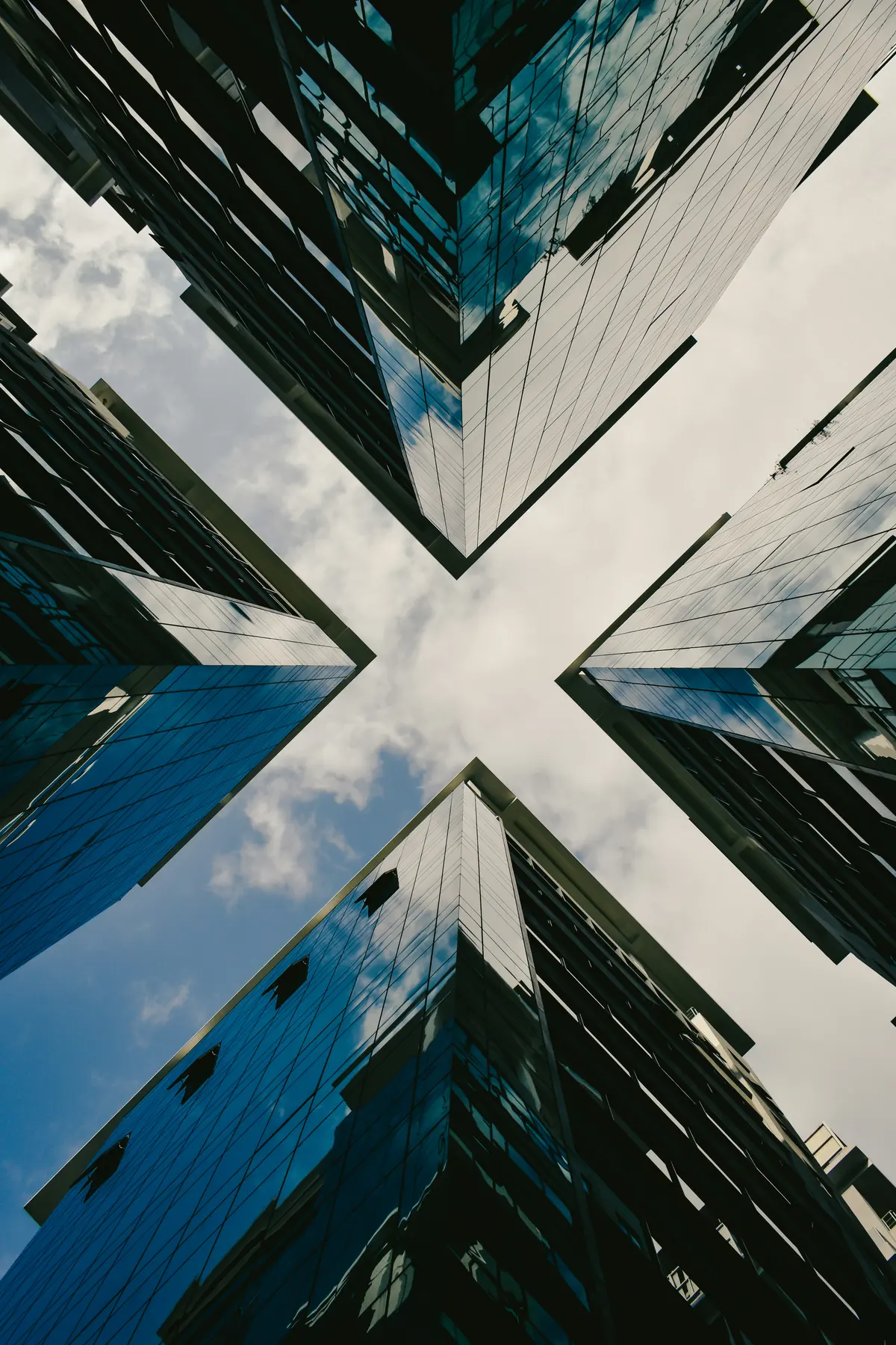 Four glass towers rising apart, meeting only at a single point in the sky